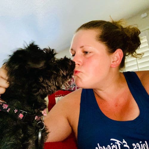 Dog trainer, Kristie Halverson, with FurBabies & Friends getting kisses from a black schnauzer.
