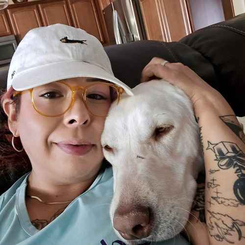 A FurBabies & Friends pet sitter gives a large white-and-tan dog extra love and attention while cuddling outdoors during a pet-sitting visit.