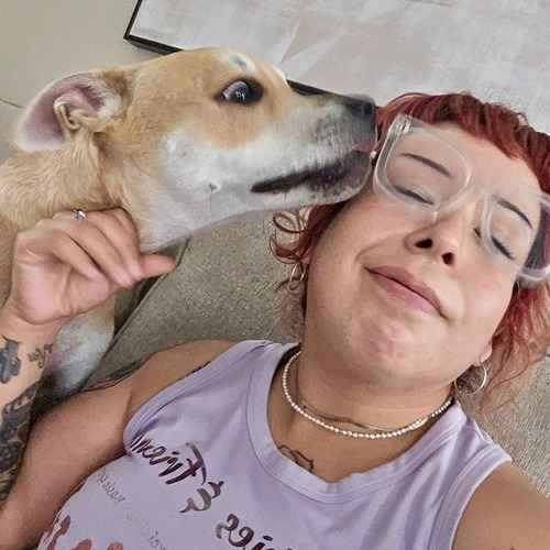 A FurBabies & Friends pet sitter receives a kiss from a tan dog while giving extra love and attention during a pet-sitting visit.