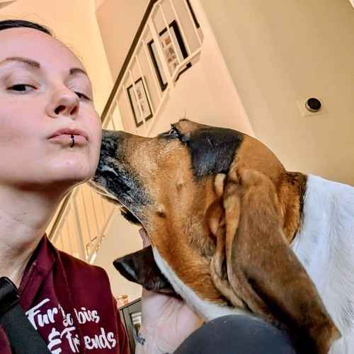 FurBabies and Friends sitter receiving a kiss from a brown-and-white dog.