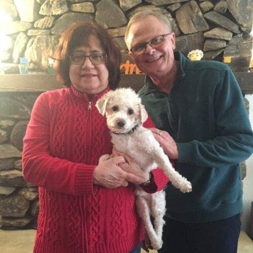 White small foster dog Ollie on his Gotcha Day with his new forever family.