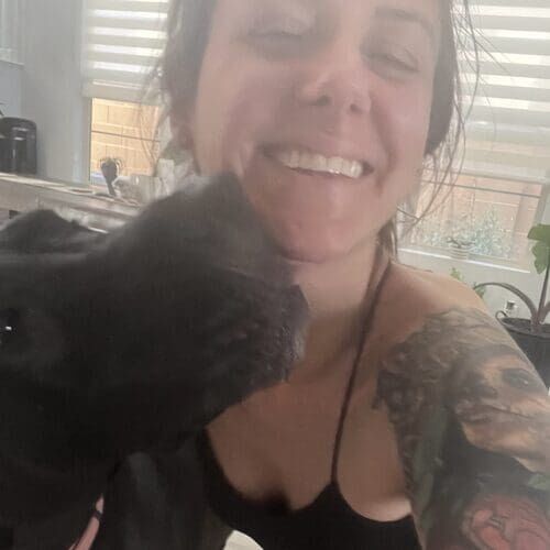 Brittany from FurBabies & Friends getting kisses from a black Great Dane during at-home pet sitting in Phoenix AZ