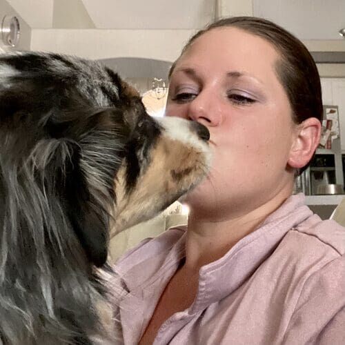 FurBabies & Friends dog trainer Kristie getting kisses from Ralphie the merle Mini Aussie in Glendale AZ