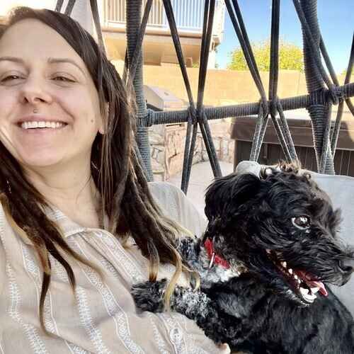 FurBabies & Friends pet sitter holding a small black dog affectionately during overnight pet sitting in Glendale AZ