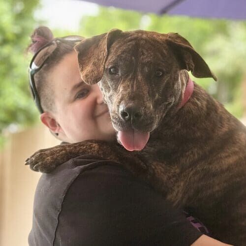 Pet sitter Vanessa from FurBabies & Friends holding a brindled Pit Bull puppy affectionately in Glendale AZ