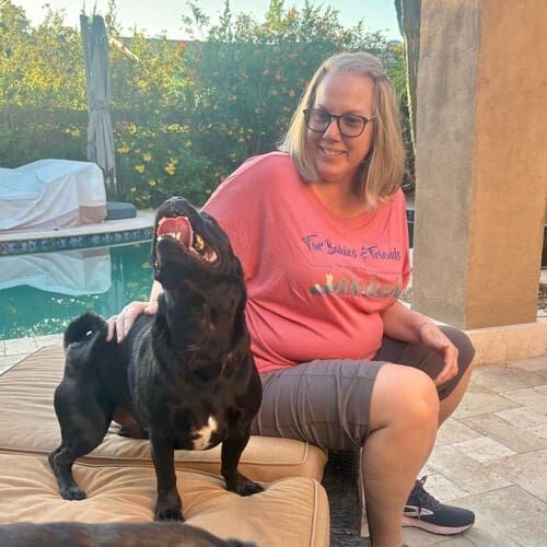 Dog sitter Karen scratches a small black dog during pet sitting in Phoenix, AZ