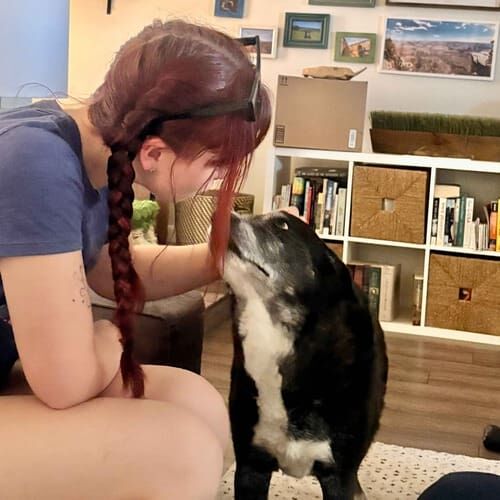 Pet sitter Camryn shows affection to a senior black dog in Glendale, AZ