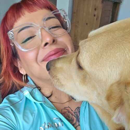 Pet sitter Nina gets kisses from a yellow Lab during at home pet sitting in Surprise, AZ
